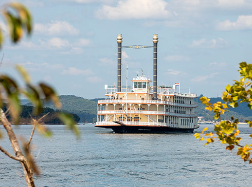 Branson Belle Showboat on Table Rock Lake framed by trees in the foreground.