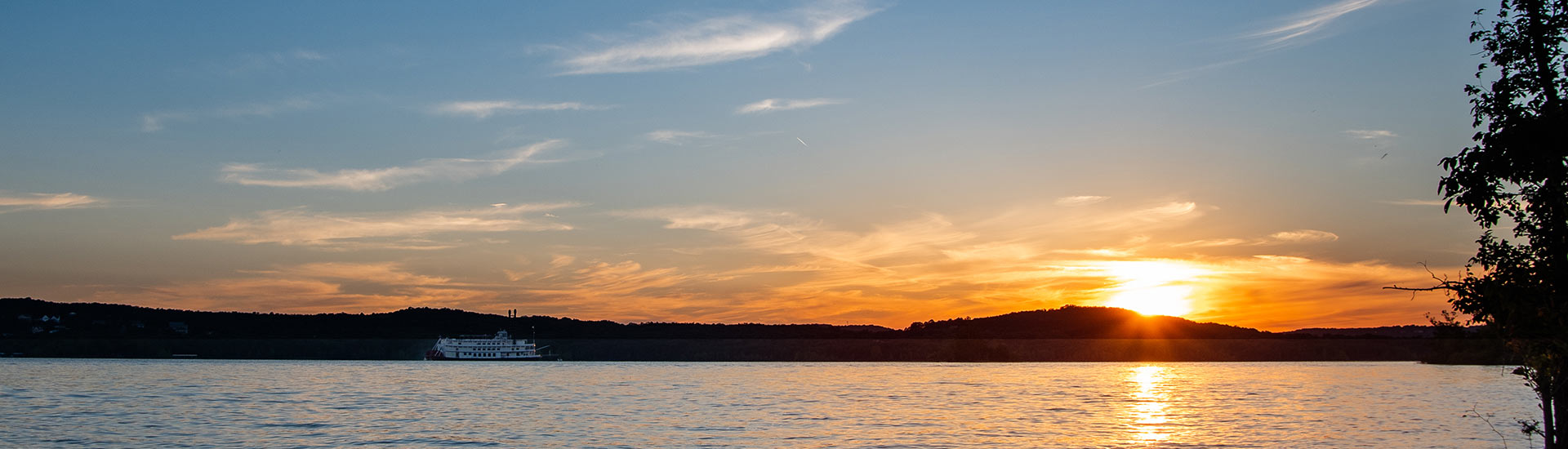 Panoramic view of a golden sunset at twilight over Table Rock Lake with the Showboat Branson Belle in the distance.