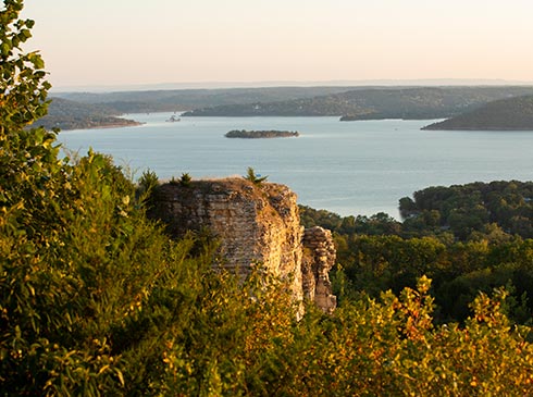View of Table Rock Lake from atop Baird Mountain with a rock outcrop in the foreground, lit by afternoon sun.