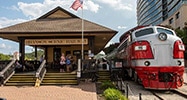 Front view of the Branson Scenic Train 98 parked next to the Branson Scenic Railway station with people on the platform.