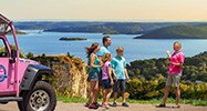 Pink® Jeep® Adventure guide and tour guests on the summit of Baird Mountain viewing Table Rock Lake, next to a Jeep® Wrangler.