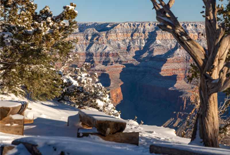 A small amphitheater sits empty and covered in snow at the South Rim’s edge with the North Rim looming large eight miles away.
