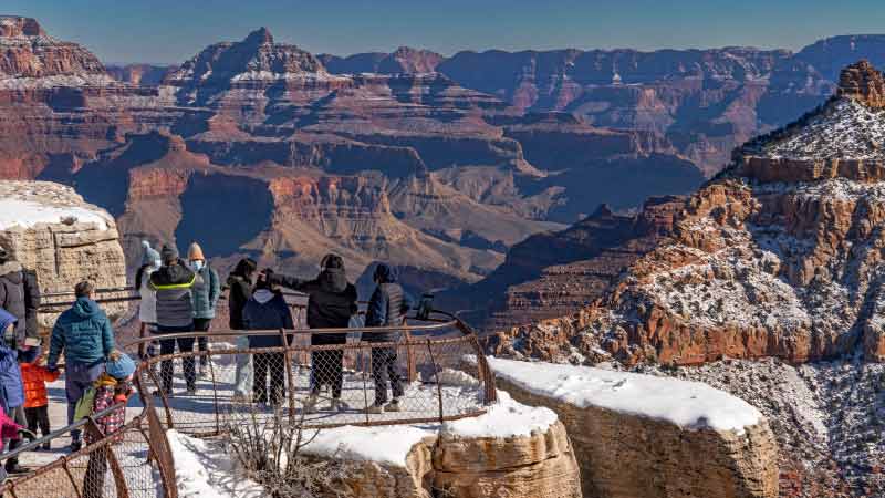 Snow covers the ground at Mather Point while tourists take in the Grand Canyon's expansive views.