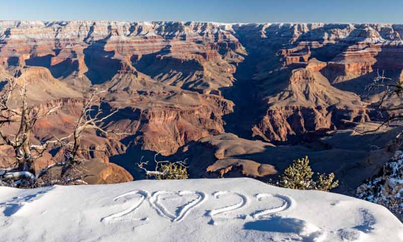 The year 2022, carved into the snow-covered ground, overlooking the Grand Canyon's South Rim in winter.