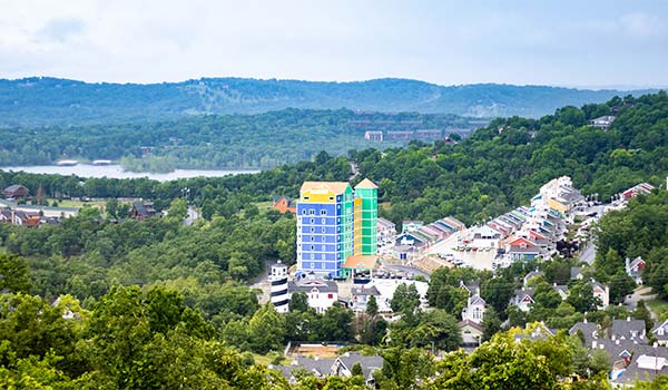 Branson's hillside and lake landscape with a brightly colored hotel and other lodging rooftops.