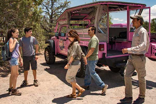 Family exiting the back of a Pink Jeep Wrangler with tour guide nearby.