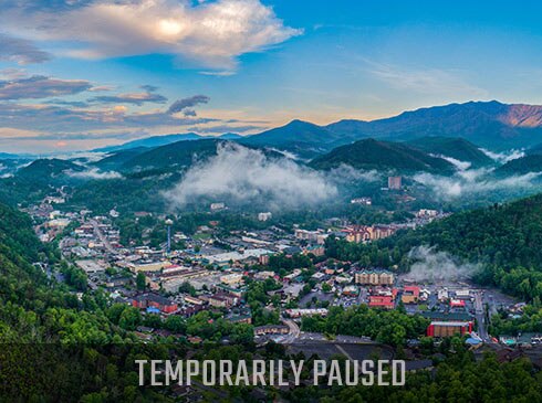 Aerial view of Downtown Gatlinburg, TN with Temporarily Paused tour header banner.