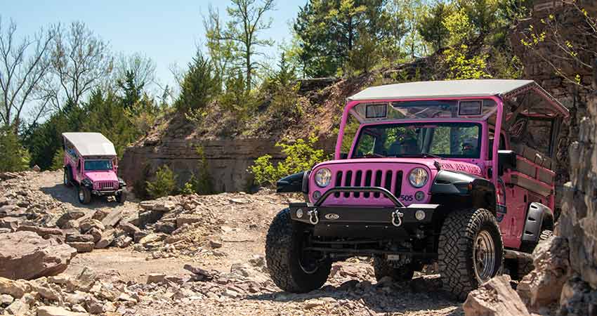 Two Pink Jeep Wranglers on tour navigate a rocky, 4x4 trail in the Baird Mountain Quarry in Branson, Missouri.