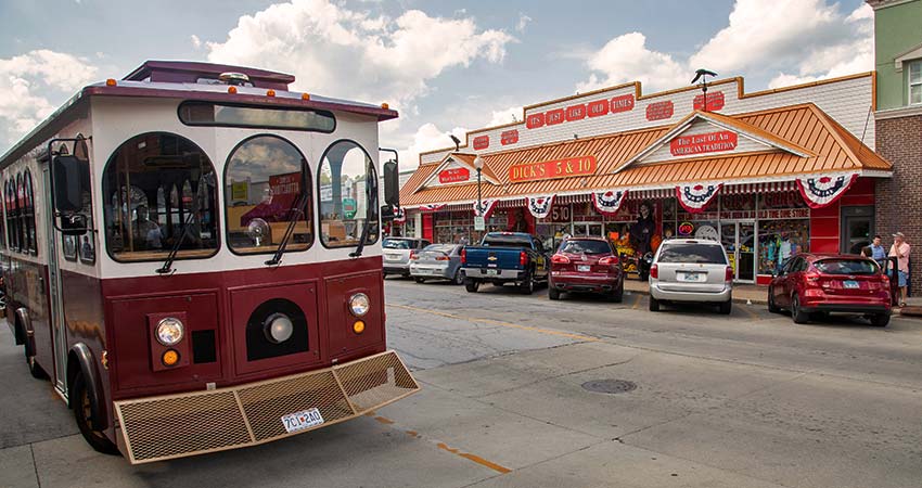 Frontal view of Sparky, the free Downtown Branson Trolley with Dick's 5&10 store across the street.