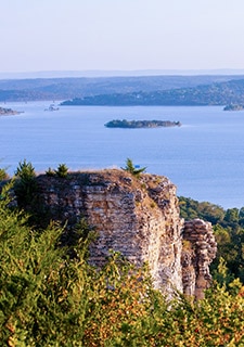 View of Table Rock Lake’s blue waters from atop Baird Mountain with a warmly lit cliff outcrop in the foreground.