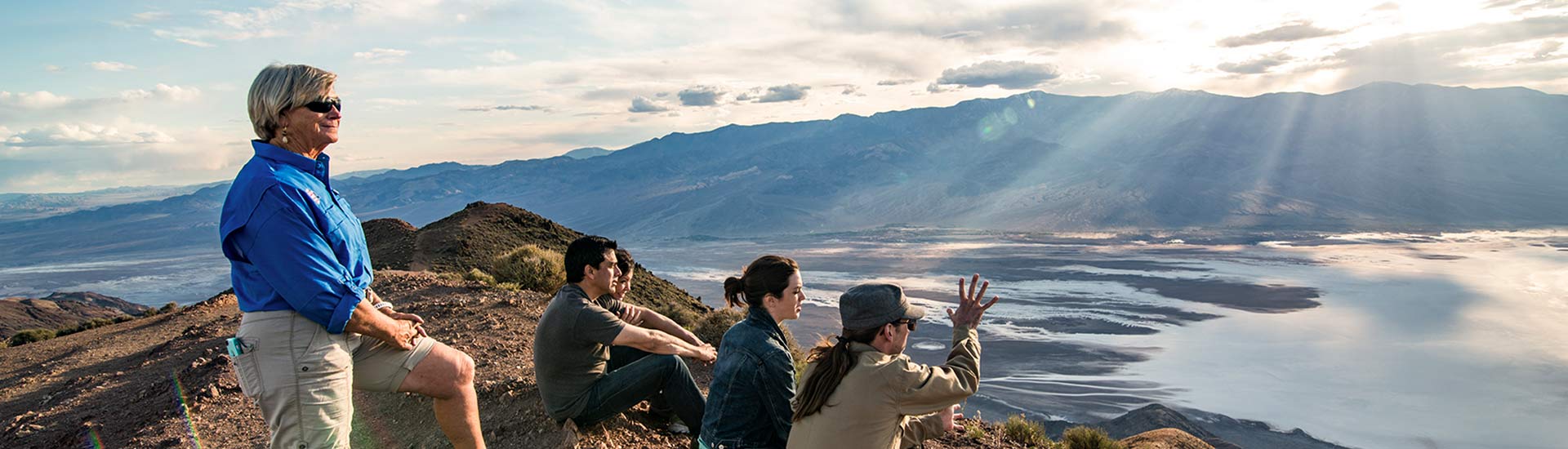 Pink Adventure guide and guests sitting atop Dante's View watching sunrise at Death Valley National Park.