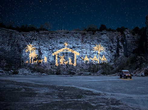 Illuminated nativity scene projected on the cliff face of Baird Mountain against a starry sky, Pink Jeep Branson Christmas Tour 2022.