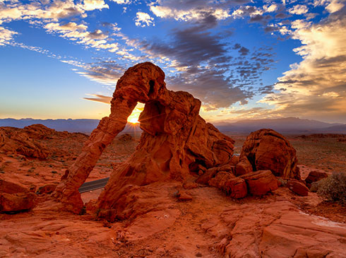 Sun setting behind Elephant Rock, Valley of Fire State Park, NV with violet blue sky and clouds at twilight.