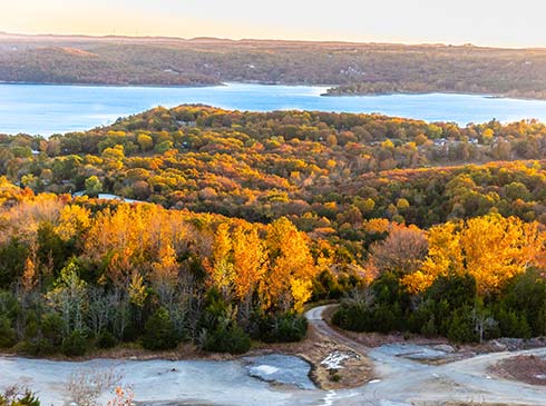 Aerial view of Pink Jeep Tours Branson’s private off-road course and Table Rock Lake, surrounded by an Autumn colored forest.