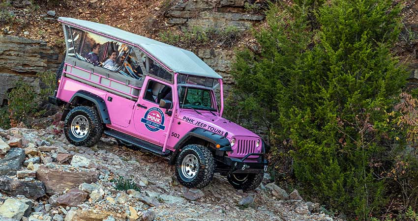 Close-up of a Pink Jeep Wrangler with tour guests navigating a steep rocky trail down into the Baird Mountain Quarry, Branson.
