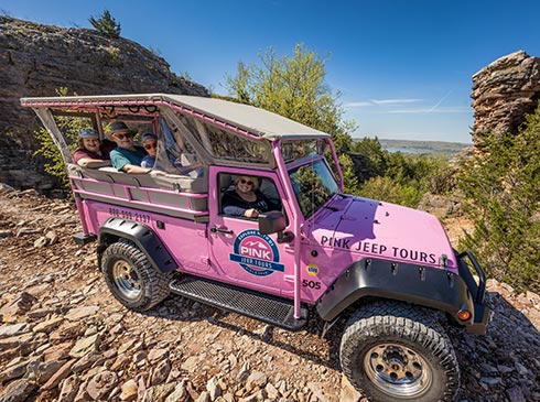 Tour guests looking out from a Pink Jeep Wrangler parked atop Baird Mountain with Table Rock Lake in background, Branson, MO.