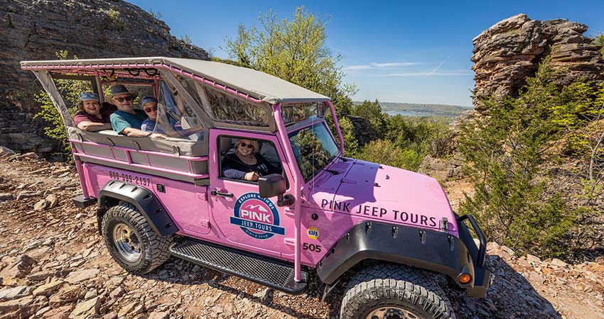Tour guests in a Pink Jeep Wrangler, parked atop Baird Mountain with view of Table Rock Lake in the distance, Branson, MO.