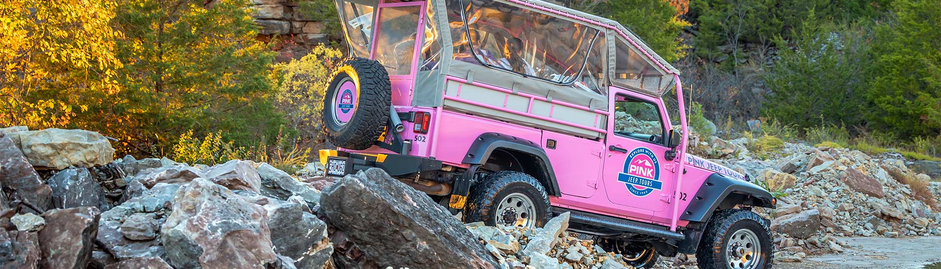 Close-up header image of golden sunlight reflecting onto the rear of a Pink Jeep Wrangler at the Baird Mountain Rock Quarry.