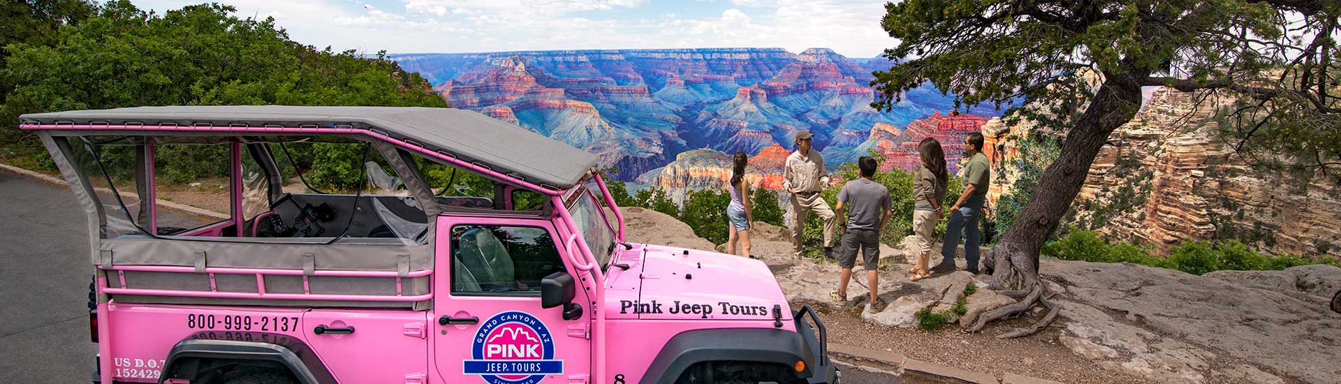 Beauty shot of tour guests standing at the Grand Canyon South Rim with a Pink Jeep Wrangler parked in foreground, Grand Canyon AZ.