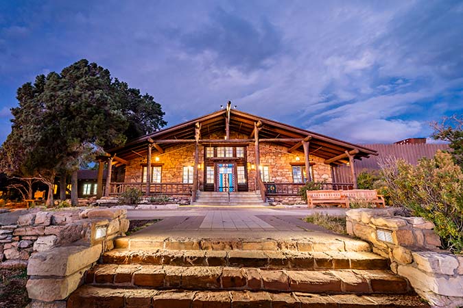 The entrance to Bright Angel Lodge, warmly lit at twilight, inside Grand Canyon National Park, USA.