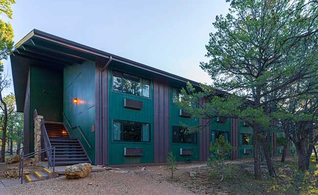 Yavapai Lodge East building surrounded by Ponderosa pines  and juniper trees under a blue sky, Grand Canyon National Park, USA.