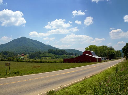 Pastoral farmland with a red barn along Wears Valley Road, TN with Smoky Mountains in the background.