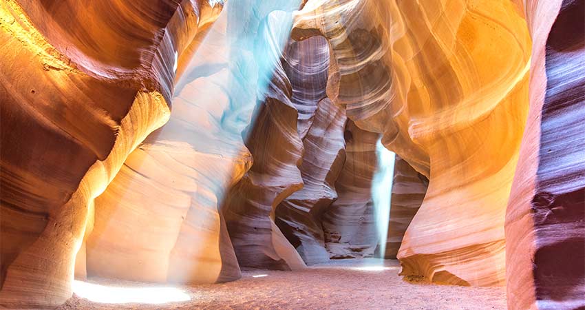 Sunbeams create a rainbow of colors reflecting off the rock formations at the bottom of Lower Antelope Canyon in Arizona.