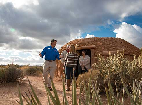 Pink Jeep guide and guests exit a traditional hogan at Hualapai Village, at Grand Canyon's West Rim