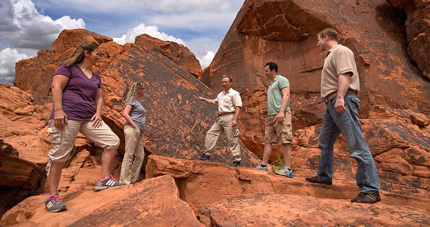 Pink Jeep Tours Las Vegas guide and guests viewing rock art on the sandstone formations at Valley of Fire State Park, NV.