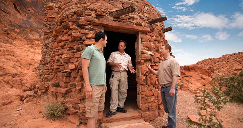 Pink Jeep Las Vegas adventure guide and two male guests touring The Cabins at Valley of Fire State Park, built in the early 1930s.