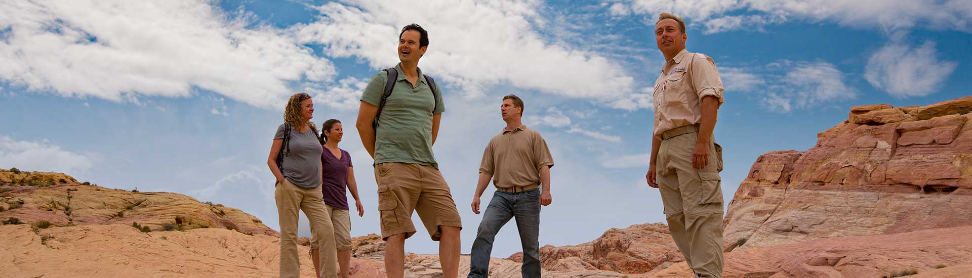 Tour guests and Pink Jeep Las Vegas adventure guide standing on a rock slab looking back over Valley of Fire State Park.