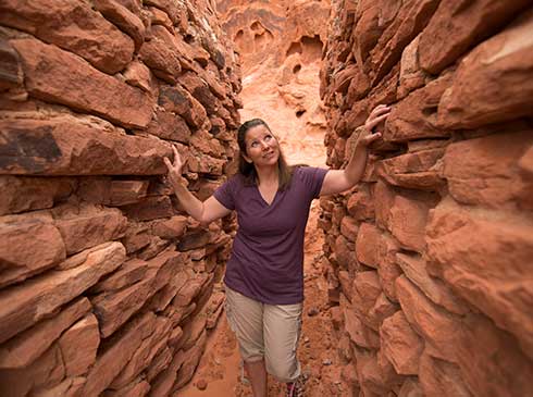 Woman walking in narrow passage between The Cabins, Valley of Fire State Park, NV