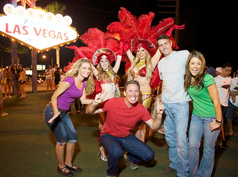 Bright Lights city tour group posing in front of "Welcome to Fabulous Las Vegas" sign at night