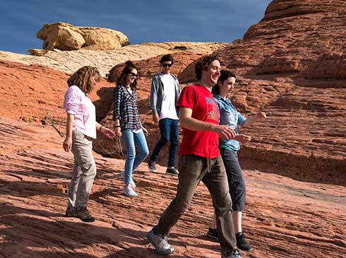 Pink Jeep tour guide and guests walking across jumbled sandstone in Red Rock Canyon National Conservation Area, NV