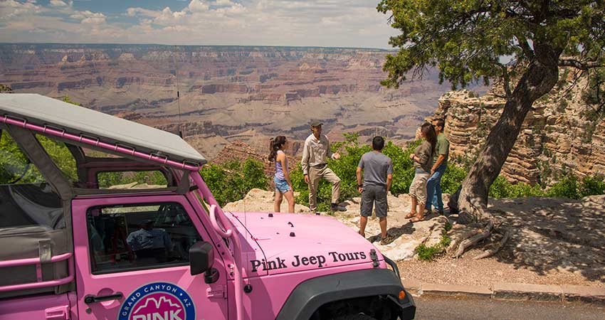 Grand Canyon Desert View Sunset tour guests with guide overlooking the South Rim with Jeep® Wrangler in foreground.