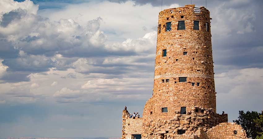 Close-up of the Desert View Watchtower along the Grand Canyon's South Rim with blue sky and puffy white clouds.