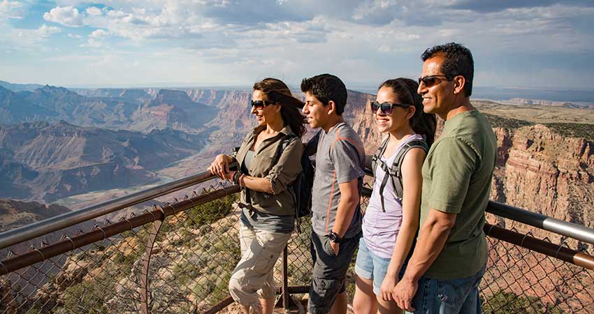 Family looking out over the Grand Canyon from a South Rim viewpoint on Pink Jeep® Tours' Desert View Sunset jeep tour 
