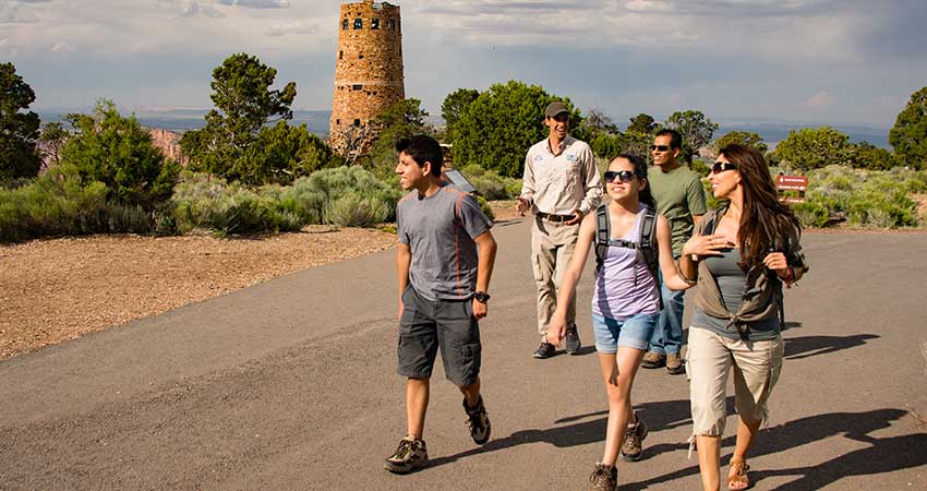 Pink Jeep Tour guide leading a family on a walk, passing the watchtower at the Grand Canyon South Rim