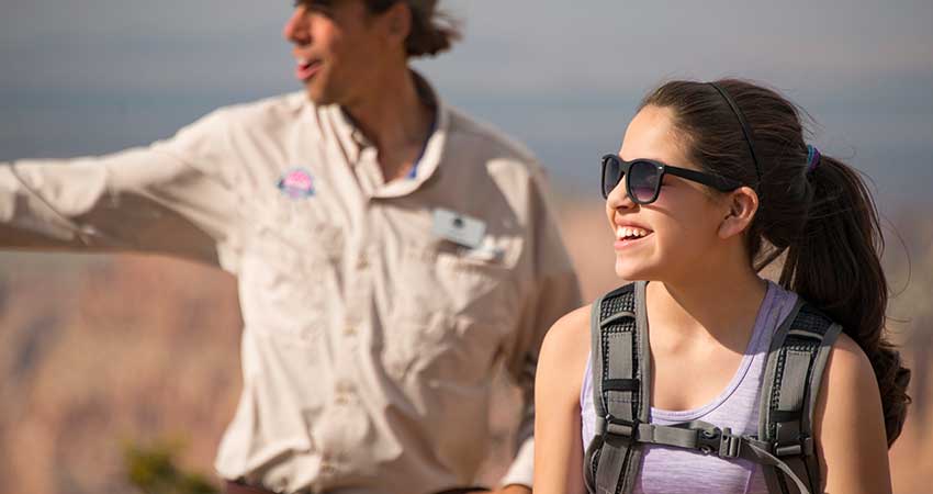 Closeup of a female guest on the Desert View Grand Canyon Tour with a Pink Jeep® Guide in the background.
