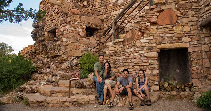 Family of four seated next to the rock stairway outside the Grand Canyon Desert View Watchtower.