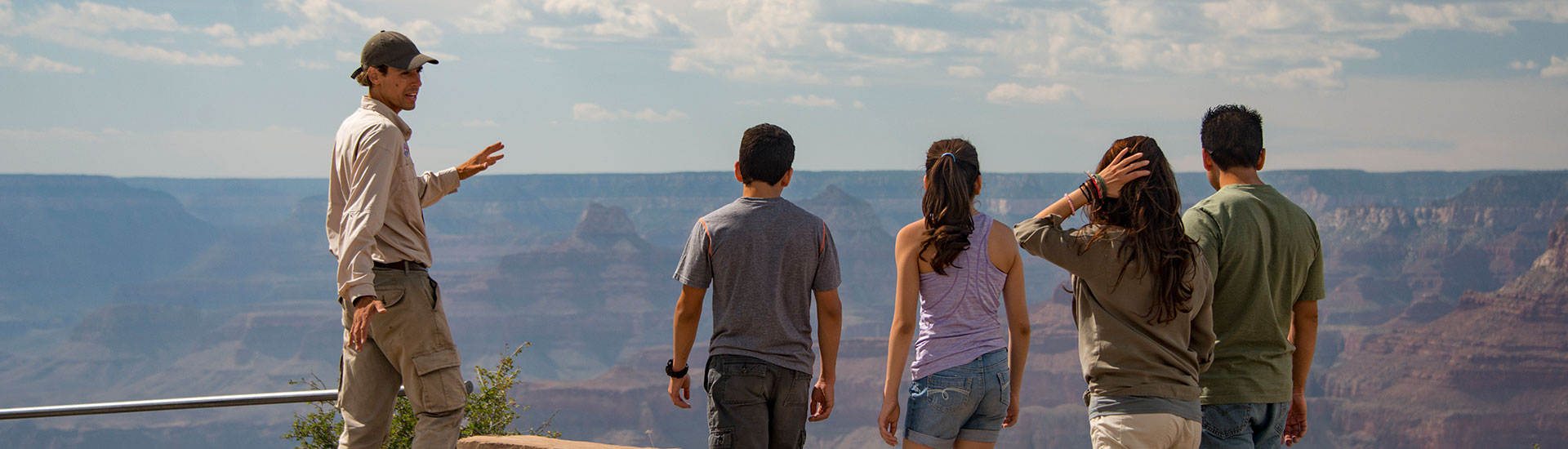 Pink Jeep® Tour guide talking to a family while overlooking the Grand Canyon's South Rim.