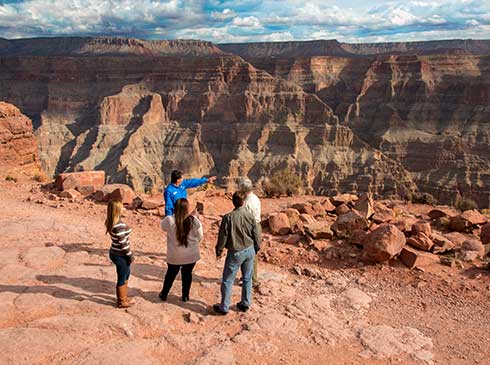 Pink Jeep tour guide pointing out geological aspects of Grand Canyon West Rim to guests 