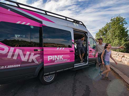 Two kids exiting from pink Mercedes Sprinter van at a Grand Canyon viewpoint, Grand Canyon Express tour 