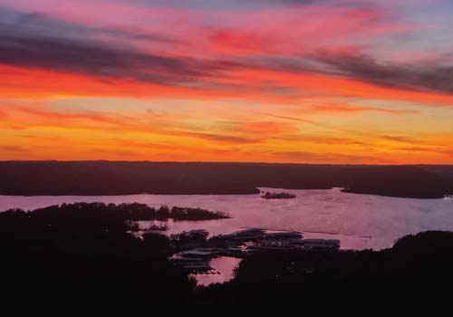 The vivid red clouds of an Ozark sunset stretch out across the horizon over Tablerock Lake in Branson, MO