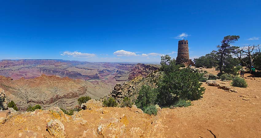 Panorama of the South Rim of the Grand Canyon with the Colorado River below and the Desert View Watchtower in the distance.