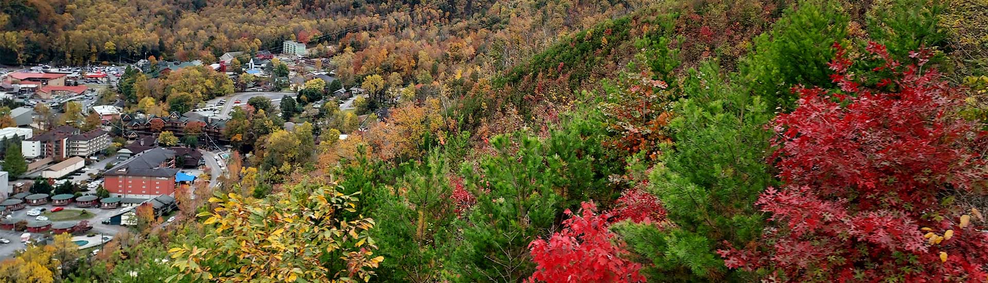 Aerial view of Downtown Gatlinburg, Tennessee during the fall with vibrant red, green and gold foliage in the foreground.
