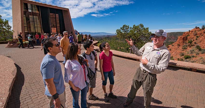 Pink Jeep Adventure guide talking with tour guests at the Chapel of the Holy Cross in Sedona, AZ during the Scenic Sedona Chapel Bells tour.