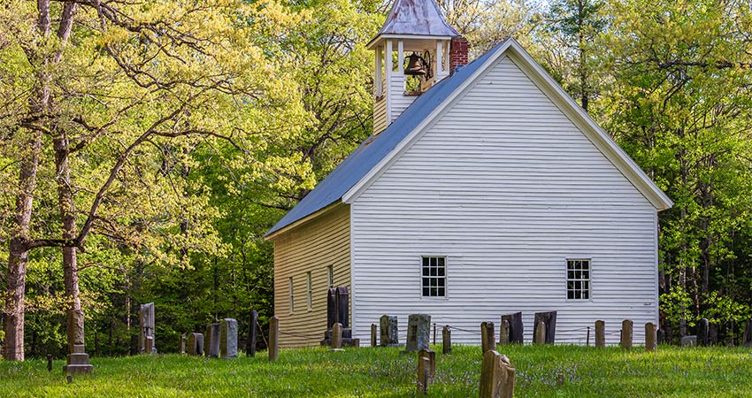 Primitive Baptist Church with cemetrey headstones around lawn, located in Cades Cove, Great Smoky Mountains National Park.
