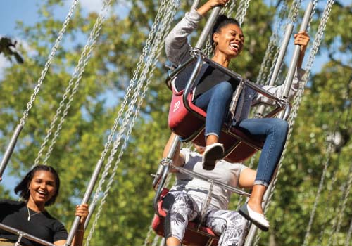 Smiling Silver Dollar City guests ride on the swings