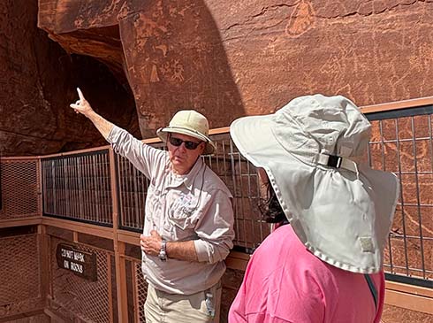 Pink Jeep Tours Las Vegas adventure guide showing a woman the pictographs on Atlatl Rock in the Valley of Fire State Park near Las Vegas.